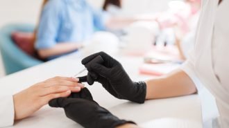 Cosmetology salon, manicure, varnish application Cosmetology salon, manicure, varnish application procedure. Hands care treatment for female client in beauty shop, woman at the cosmetologist, master works with fingernails